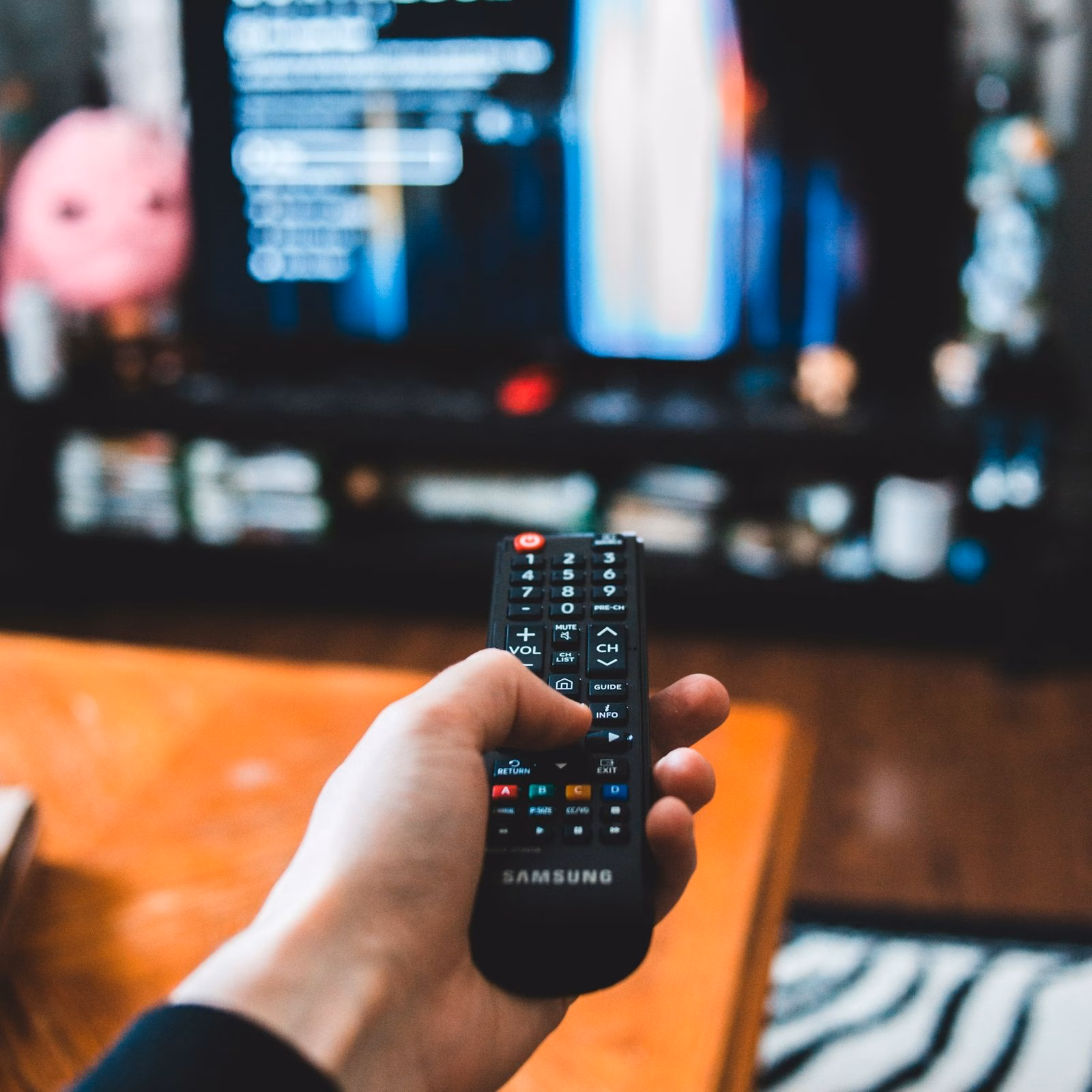 Hand holding a remote in front of a streaming TV menu